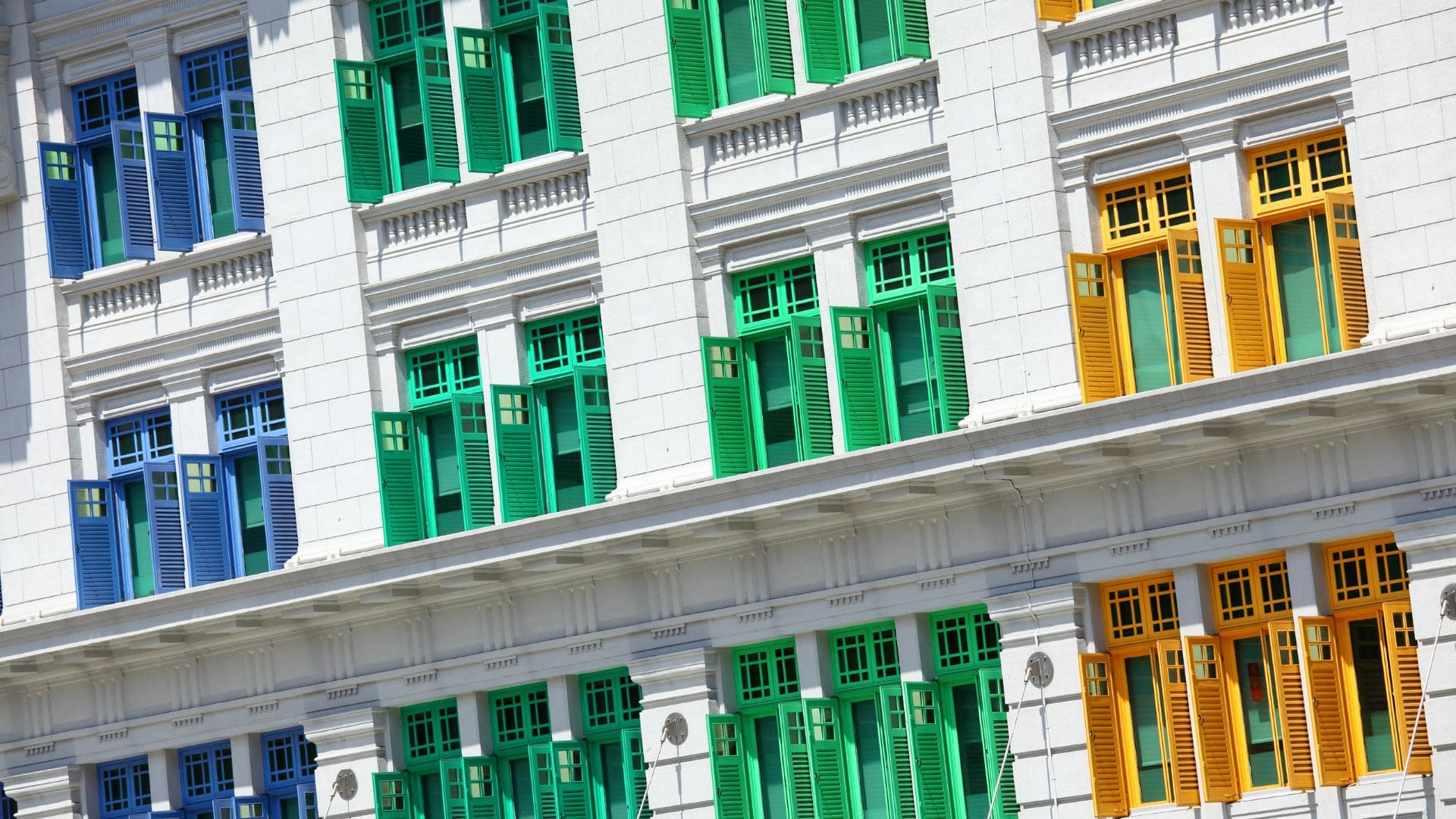 Volets en bois peints en bleu, vert et jaune sur la façade d'un bâtiment